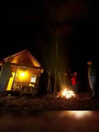 People standing around a campfire outside a cabin